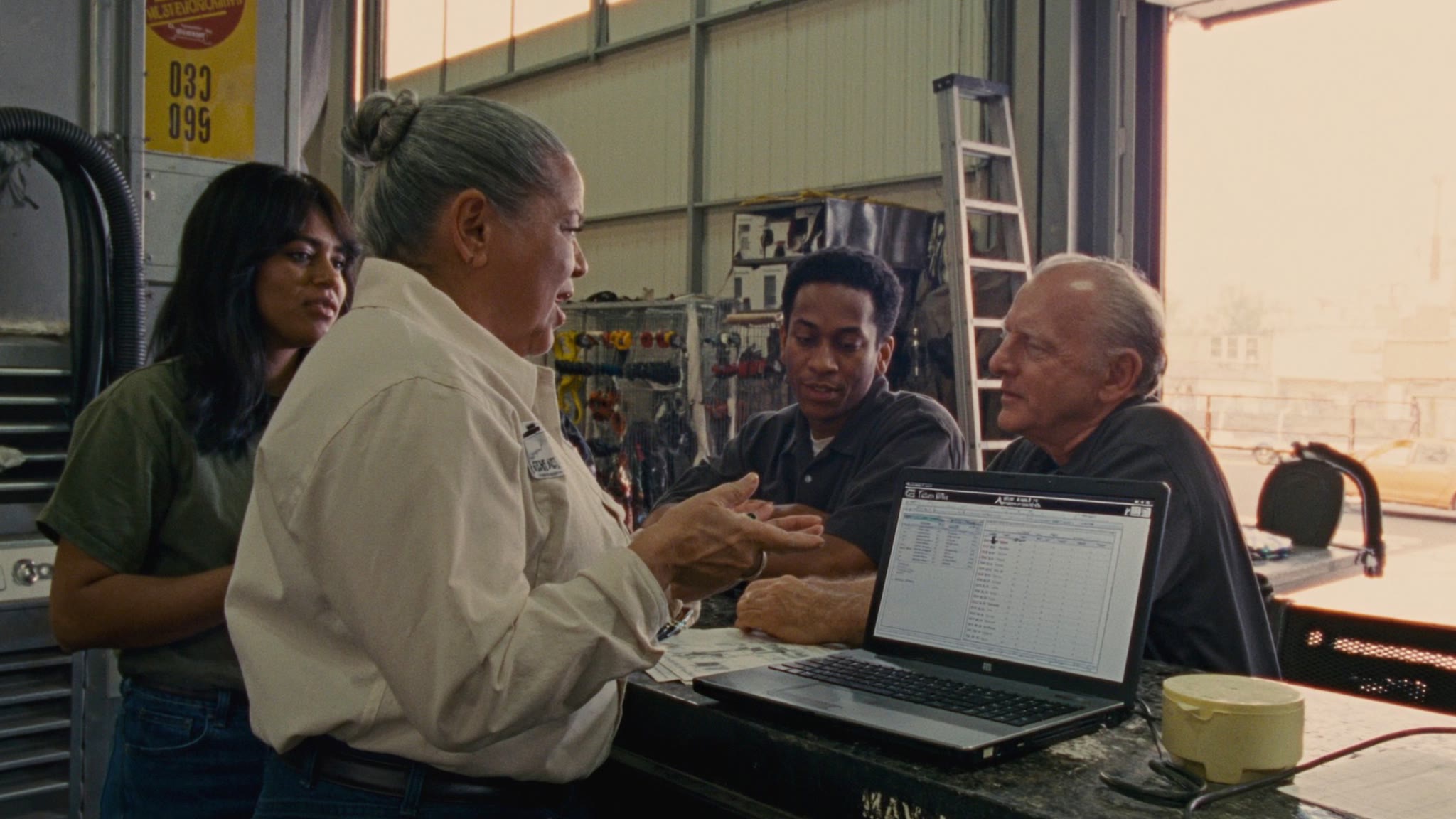 A service crew talking through a job at the counter, a laptop open in front of them