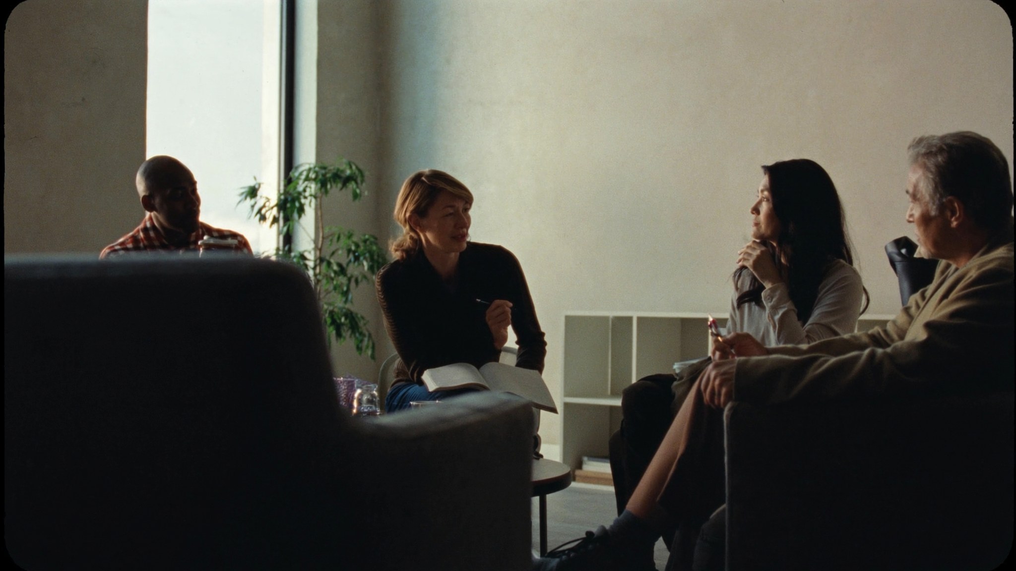 A small HR team in an unhurried working conversation around a low table in a quiet office